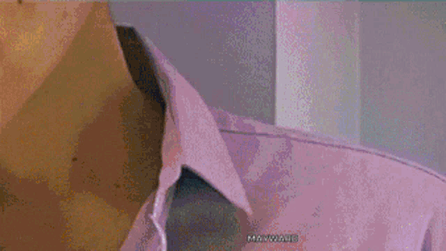 a man in a purple shirt is drinking orange juice from a glass
