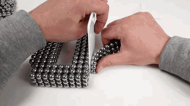 a person is holding a piece of paper between two rows of metal balls