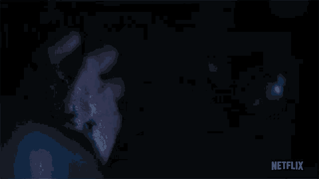 a person 's hand is reaching out in the dark with a netflix logo behind them .