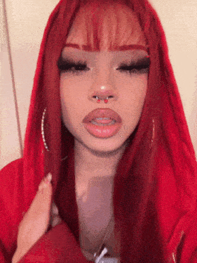 a girl with red hair and a nose ring is wearing a red hoodie