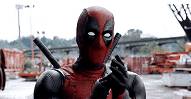 a man in a deadpool costume is holding a gun in his hands .