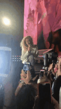 a woman is singing into a microphone while a crowd watches