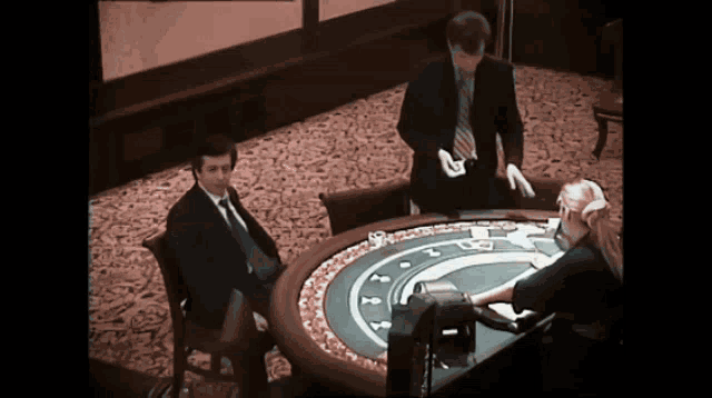 a man in a suit and tie stands behind a roulette table while a woman plays