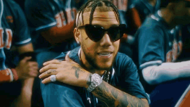 a man wearing sunglasses and a watch is sitting in a crowd of people