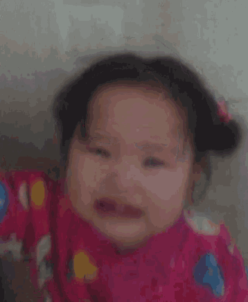 a baby girl is crying and wearing a pink jacket with a cat on it .