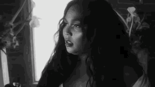 a black and white photo of a woman with long hair in a room .