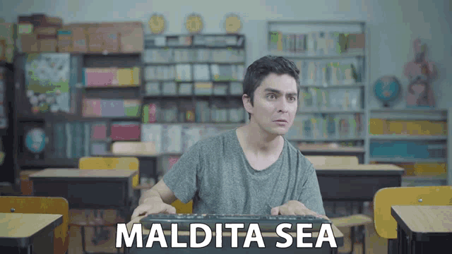 a man sitting in a classroom with the words maldita sea on the bottom
