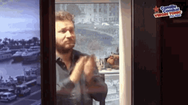 a man applauds in front of a sign that says camille combal virgin tonic