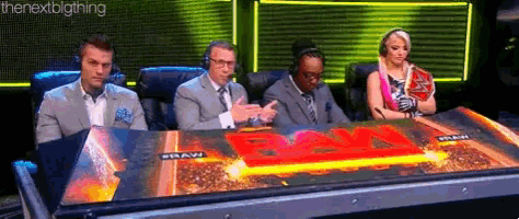 a group of people are sitting at a table with a sign that says raw on it .
