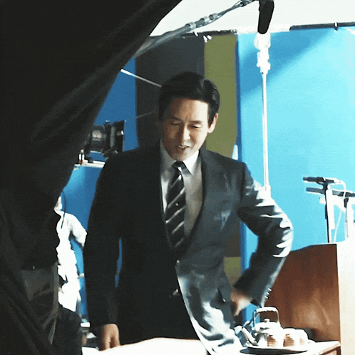 a man in a suit and tie standing in front of a blue wall