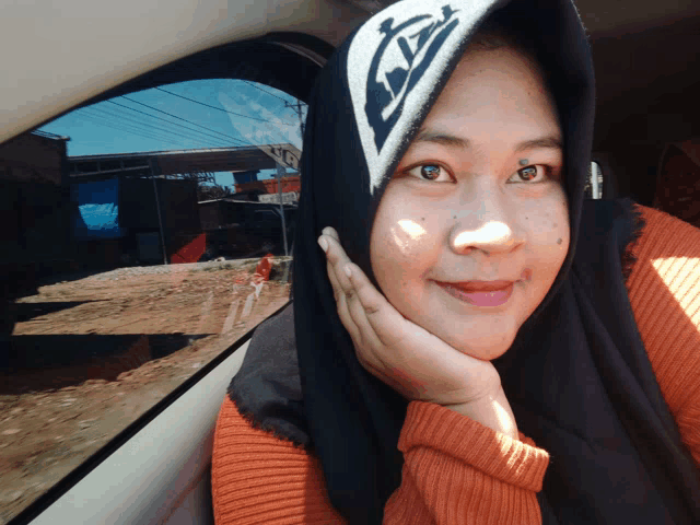 a woman wearing a hijab and a hat with the letter a on it