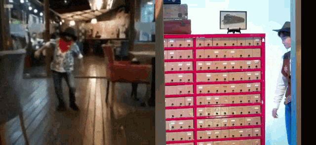 a man in a cowboy hat is standing in front of a row of mailboxes