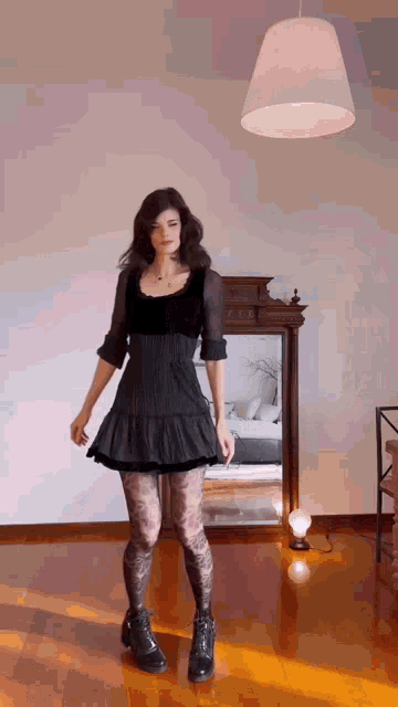 a woman in a black dress is standing in front of a mirror
