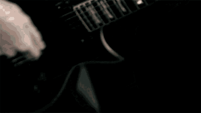 a person playing an electric guitar with a black background