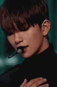 a close up of a person wearing a black turtleneck and a microphone in their mouth .