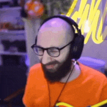 a bald man with a beard and glasses is wearing headphones .