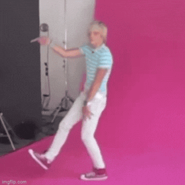 a man in a blue shirt and white pants is dancing on a pink rug .