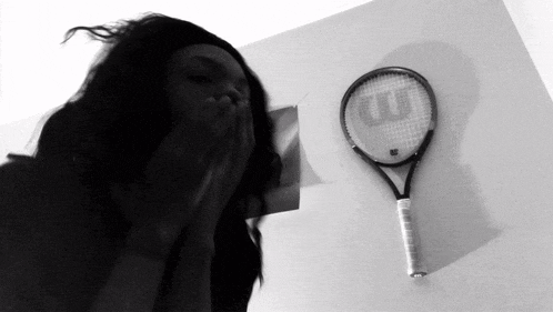 a black and white photo of a woman covering her mouth next to a wilson tennis racket