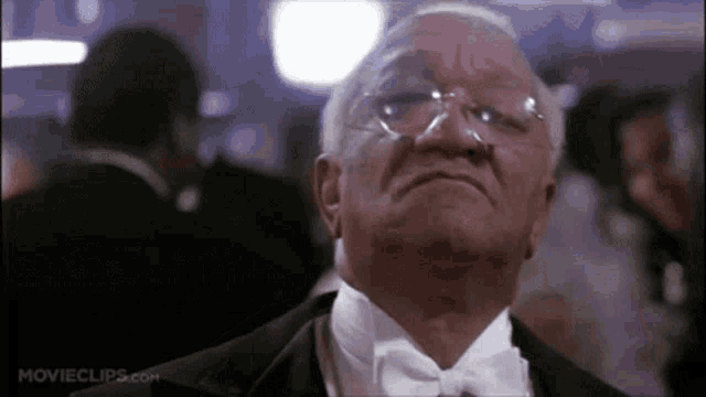an older man in a tuxedo and bow tie is looking up at the sky .
