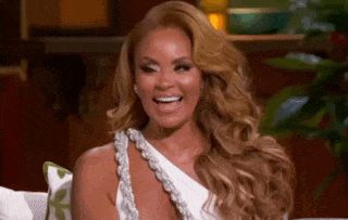 a woman is sitting on a couch wearing a white dress and smiling .