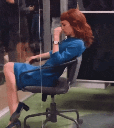 a woman in a blue dress sits on an office chair