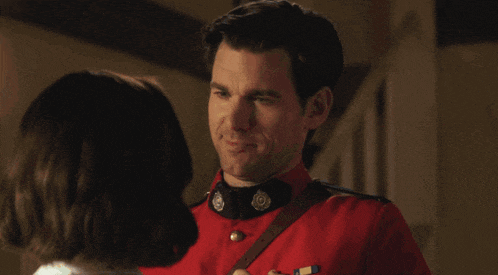 a man in a red uniform is kissing a woman in a white dress