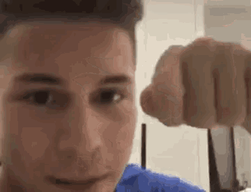 a close up of a man 's face with his fist pointing at the camera .