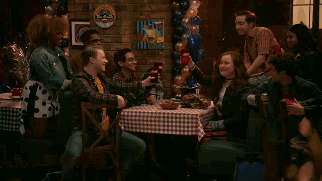 a group of people toasting at a table in front of a sign that says ' the queen '