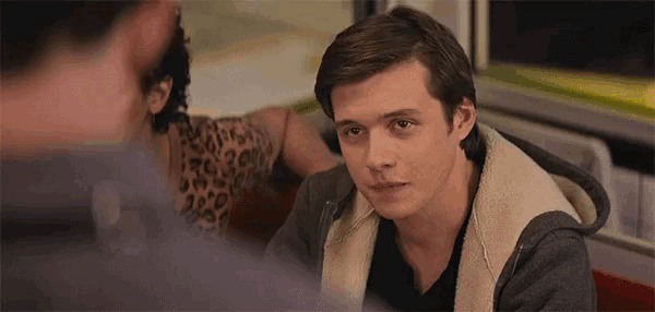a young man is sitting at a table in a diner looking at another man .