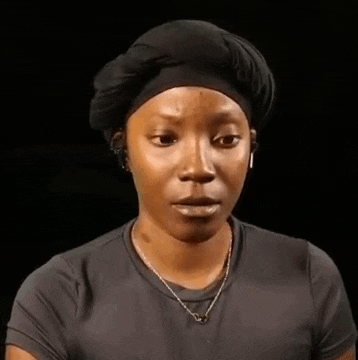 a woman wearing a black headband and a necklace is making a surprised face .
