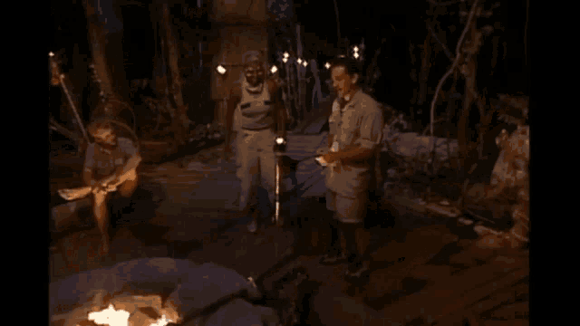a group of people standing around a fire in a dark room