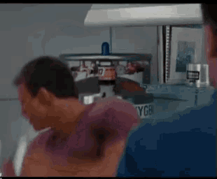 a man in a purple shirt is standing next to another man in a blue shirt in front of a machine that says ygb