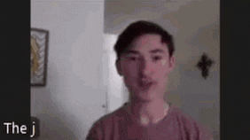 a young man is talking on a video call while wearing a pink t-shirt .