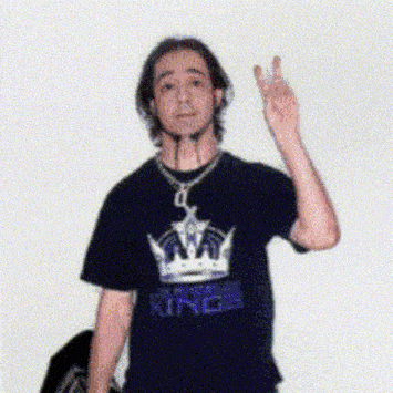 a man wearing a t-shirt that says king giving a peace sign