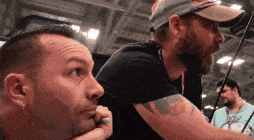 a man with a tattoo on his arm is looking at another man