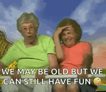 two elderly women are sitting next to each other on a bench with the caption `` we may be old but we can still have fun '' .