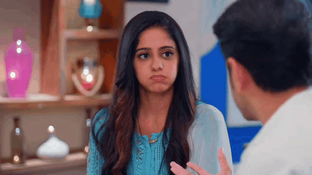 a woman in a blue dress is making a face while talking to a man in a white shirt .