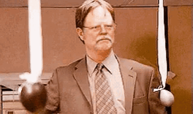 a man in a suit and tie is holding a sword in his hand .