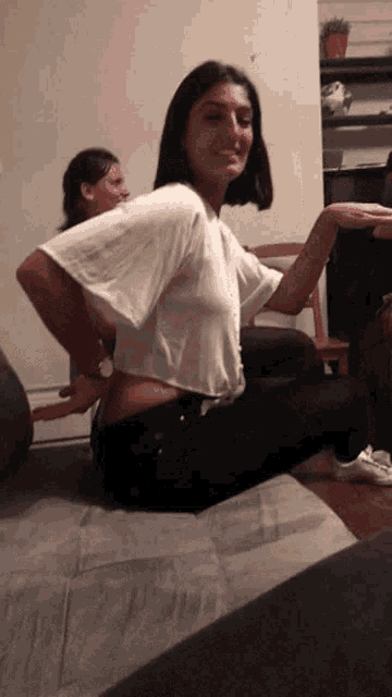 a woman in a white crop top is sitting on a couch