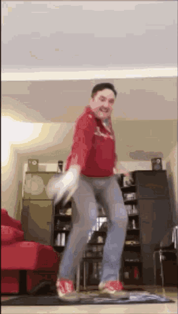 a man in a red shirt and gray pants is dancing