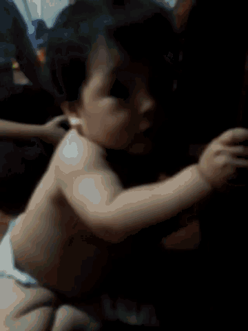 a baby in a diaper is being held by a person and smiling