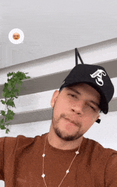 a man wearing a brown shirt and a black hat has a smiley face above his head