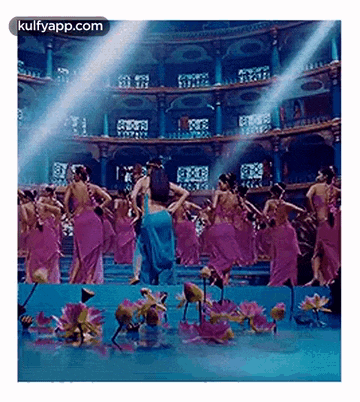 a group of women are dancing in front of a large building surrounded by water lilies .