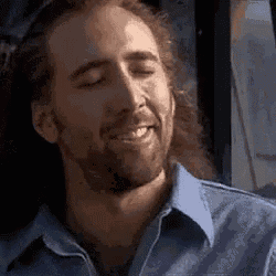 a man with long hair and a beard is smiling with his eyes closed while sitting on a bus .