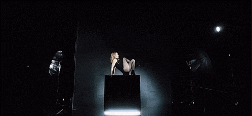 a woman is laying on a box with her legs crossed in a dark room