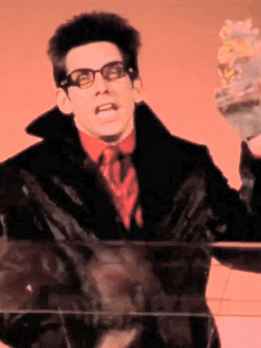 a man wearing glasses and a black coat is holding a glass container