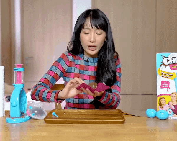 a woman sits at a table with a box of choco balls on it