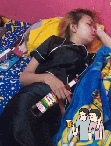 a person laying on a bed holding a bottle that says ' merah ' on it