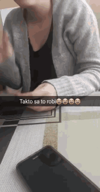 a woman is sitting at a table with a phone and a text that says " takto sa to robi "