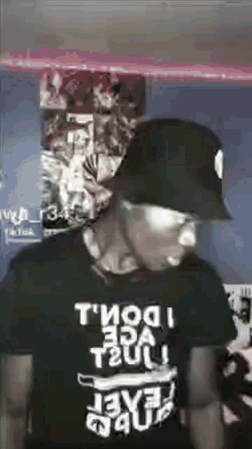 a man wearing a hat and sunglasses is standing in front of a wall with posters .